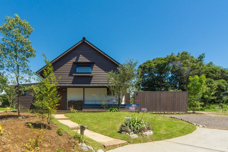 三角屋根の緑に包まれたシンケンスタイルの木の家