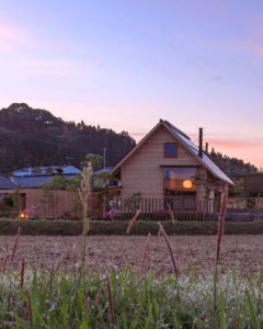 夕焼けの田園風景に馴染む三角屋根の家